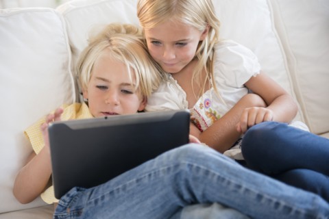 Girl (6-7) and boy (4-5) looking at digital tablet