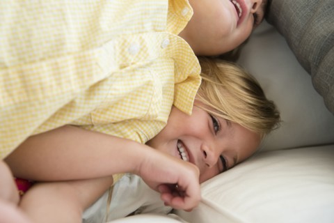 Boy (4-5) and girl (6-7) playing on sofa