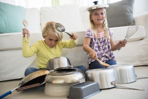 Boy (4-5) and girl (6-7) playing on pots on living room