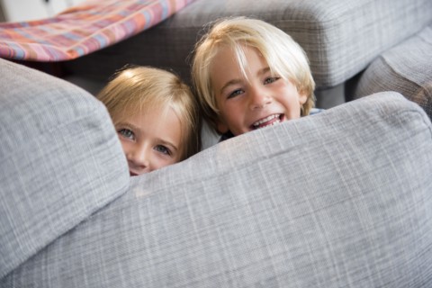 Boy (4-5) and girl (6-7) hiding behind pillows