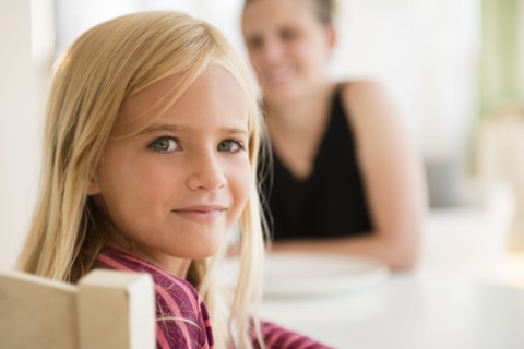 Girl (6-7) looking at camera and woman in background