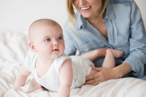 Baby girl (12-17 months) with mother on bed