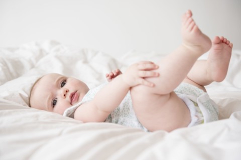 Baby girl (12-17 months) lying down on bed