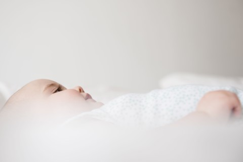 Baby girl (12-17 months) lying down on bed