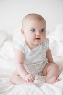 Baby girl (12-17 months) sitting on bed