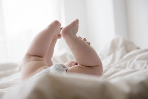 Baby girl (12-17 months) lying down with legs up