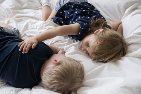 Brother (2-3) with sister (2-3) sleeping on bed