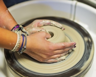 Woman shaping clay bowl on pottery wheel