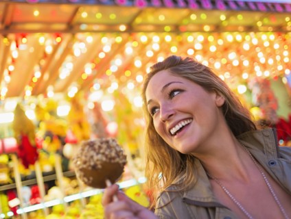 Woman holding caramel apple at funfair