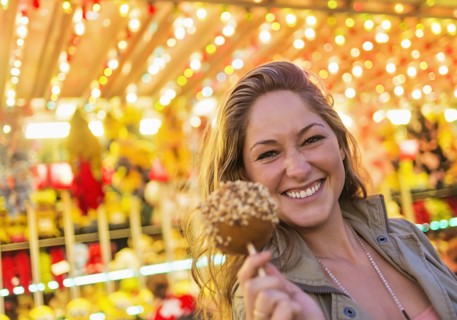 Woman holding caramel apple at funfair