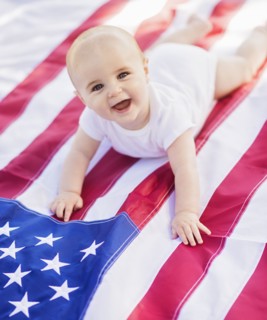 Baby boy (6-11 months) lying on American flag