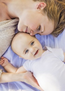 Mother lying down with baby boy (6-11 months)