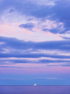 Pastel-colored sunset seascape with sailboat