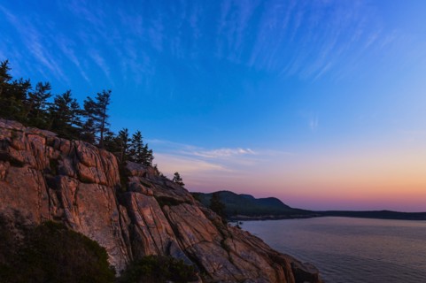 Rocky cliff by sea at sunrise