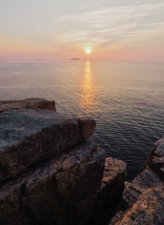 Rocky cliff by sea at sunrise