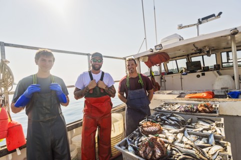 Portrait of three fishermen standing on boat
