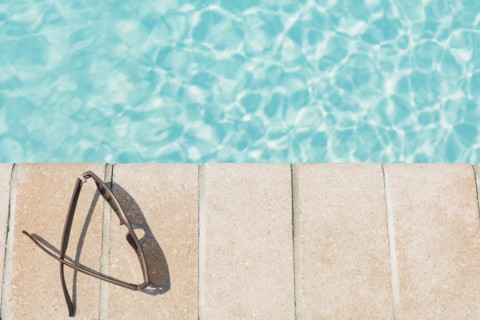 Sunglasses on brick ledge by pool