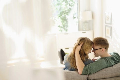 Young couple sitting face to face on sofa.