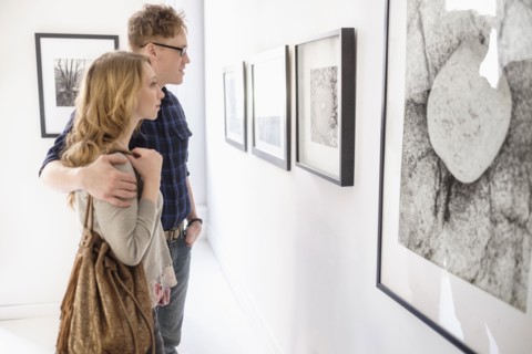 Young couple looking at photographs at museum.