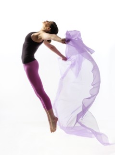 Woman with sheer fabric jumping.
