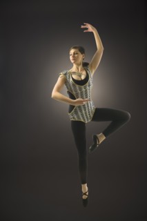 Young woman dancing against black background.