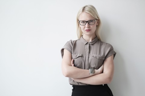 Young woman standing against white wall.