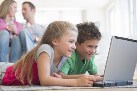 Boy and girl (6-7, 8-9) lying on floor and using laptop