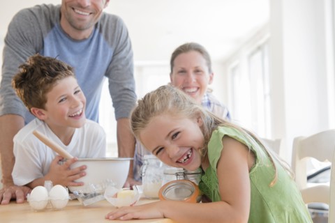 Family with two children (6-7, 8-9) preparing food, laughing