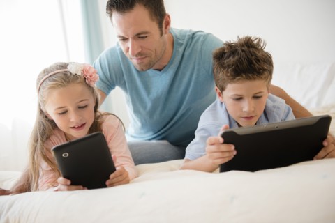 Father with son (8-9) and daughter (6-7) using tablets