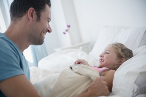Father tucking daughter (6-7) in bed