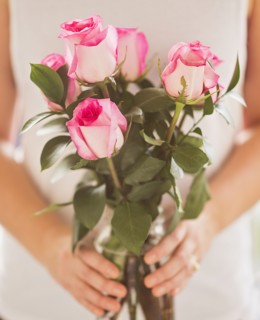 Mid section of woman holding bunch of pink roses