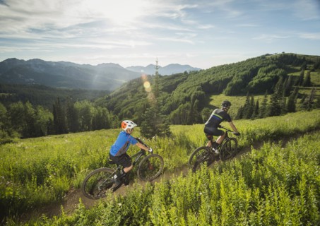 Father and son (10-11) cycling in mountains