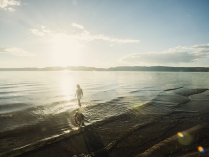 Small girl (4-5) wading in lake on sunny day