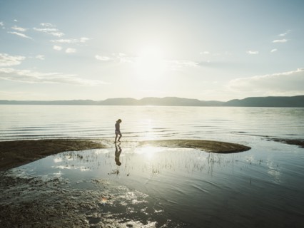 Small girl (4-5) wading in lake on sunny day
