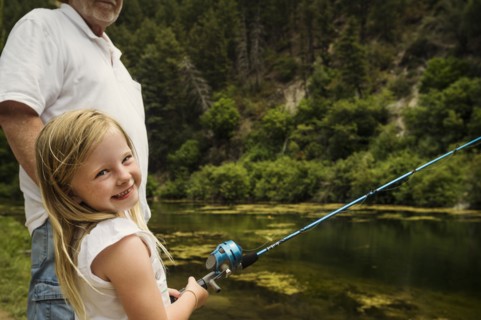 Small girl (4-5) fishing with grandfather