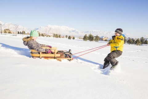 Children (8-9) playing with sled in snow
