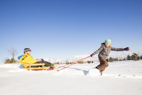 Children (8-9) playing with sled in snow