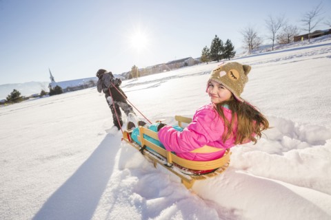 Children (8-9, 10-11) playing with sled in snow