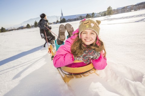 Children (8-9, 10-11) playing with sled in snow