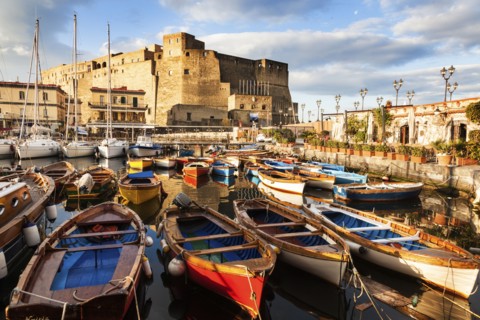 Colorful boats and Castel dell' Ovo at night