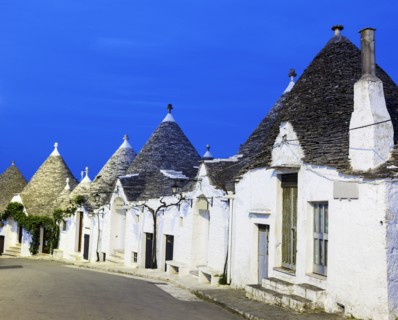 Trulli houses along street under blue sky
