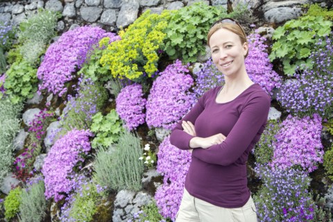 Smiling woman standing against flowerbed