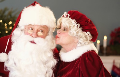 Mrs. Claus kissing Santa on cheek.
