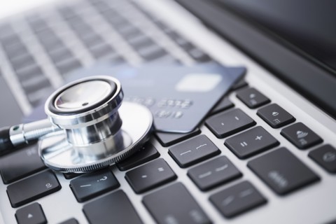 Stethoscope and credit card lying on laptop.