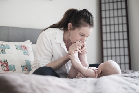 Mother kissing baby daughter's (2-5 months) feet.