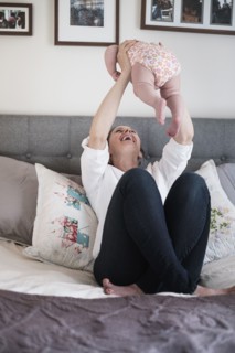 Mother playing with baby daughter (2-5 months) in bedroom.