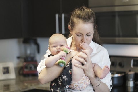 Mother kissing baby daughter's (2-5 months) feet.