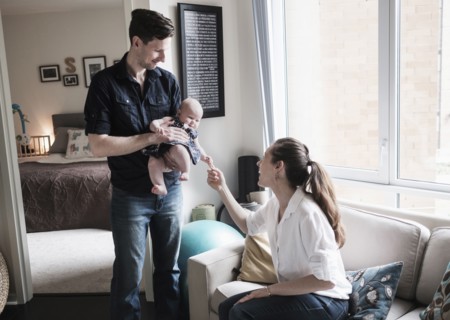 Parents playing with baby daughter (2-5 months) in living room.