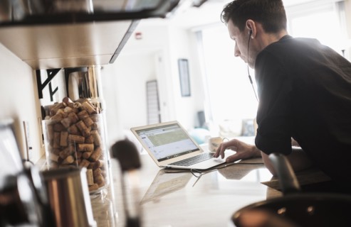 Man working on laptop computer in kitchen.