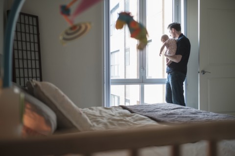Father looking through window with daughter (2-5 months).